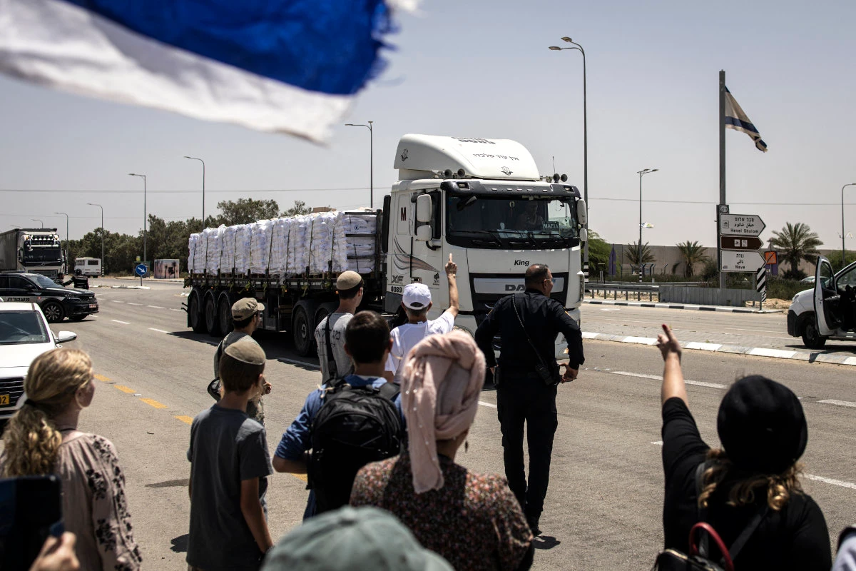 Right-wing protesters gesture at a truck driving past during a protest to block humanitarian aid from entering Gaza at the Kerem Shalom crossing on May 21, 2025. (AFP/File)