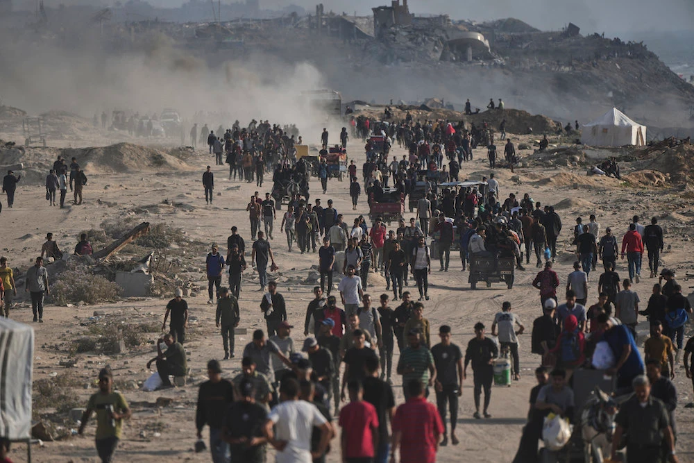 Displaced Palestinians walk past the ruins of destroyed buildings along the Gaza City shoreline on Monday, June 9, 2025. (AP)