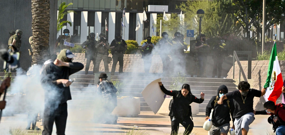 Protesters run from police as they use tear gas and flash-bangs at the Federal Building in Santa Ana, California, on June 9, 2025. (The Orange County Register via AP)