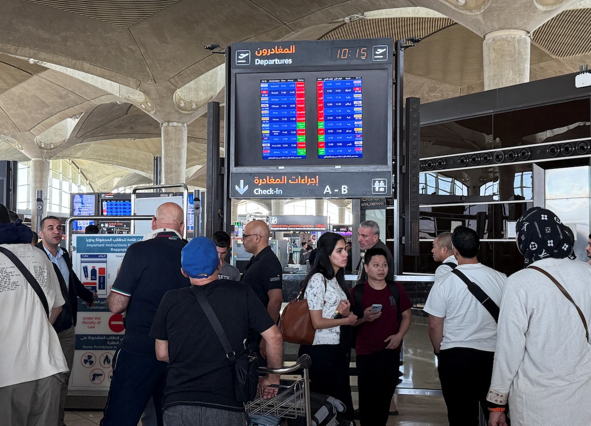 People stand in front of a flight information display screen showing information about delayed and cancelled flights, at Queen Alia International Airport in Amman, Jordan June 13, 2025. (Reuters)