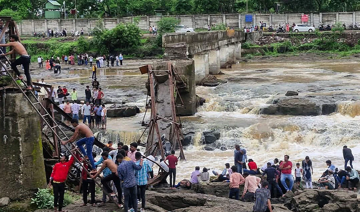 People gather near the site of a bridge collapse at Indrayani river near Kundamala village in Pune on June 15, 2025. (AFP)
