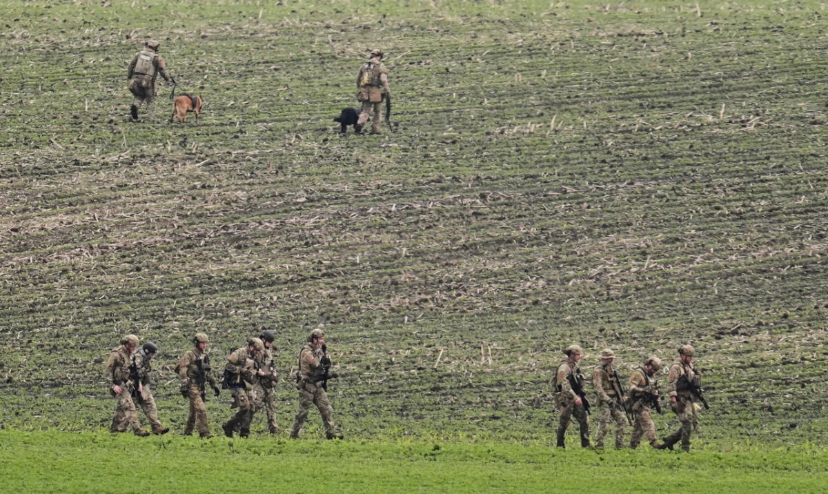 Members of law enforcement agencies walk through a field near a vehicle suspected to belong to shooting suspect, Vance Boelter, Sunday, June 15, 2025, in Belle Plaine, Minn. (AP)