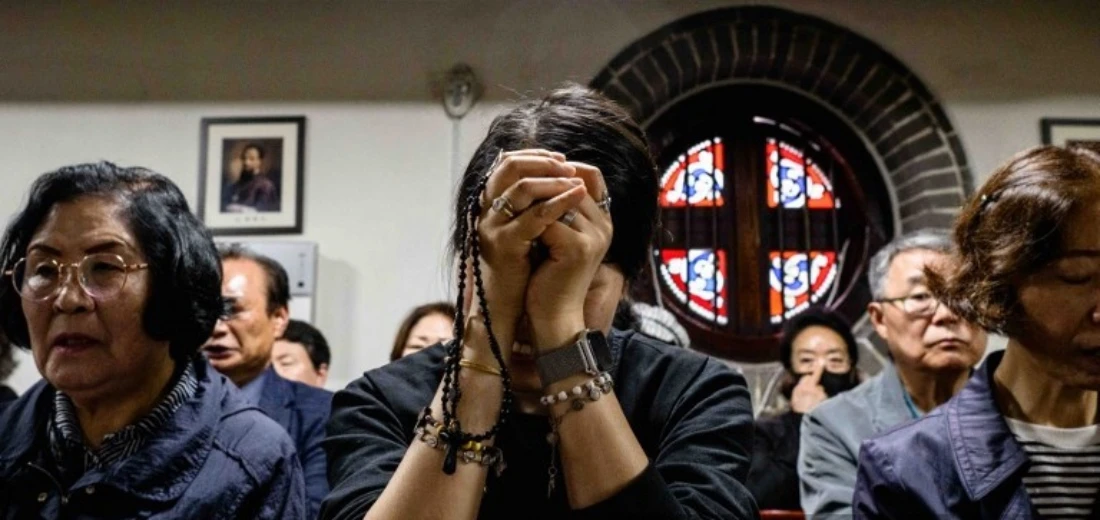 People pray as they pay their respects near a portrait of Pope Francis displayed inside Myeongdong Cathedral in Seoul, South Korea. (AFP)
