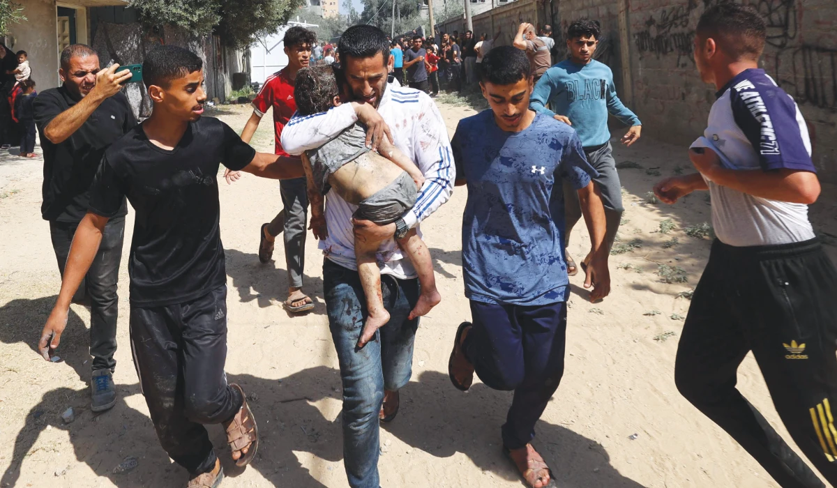 Palestinians rush a wounded child in Al-Bureij camp in the central Gaza Strip after the area was targeted by an Israeli strike, on June 17, 2025, amid the ongoing conflict between Israel and the Palestinian Hamas militant group. (AFP)