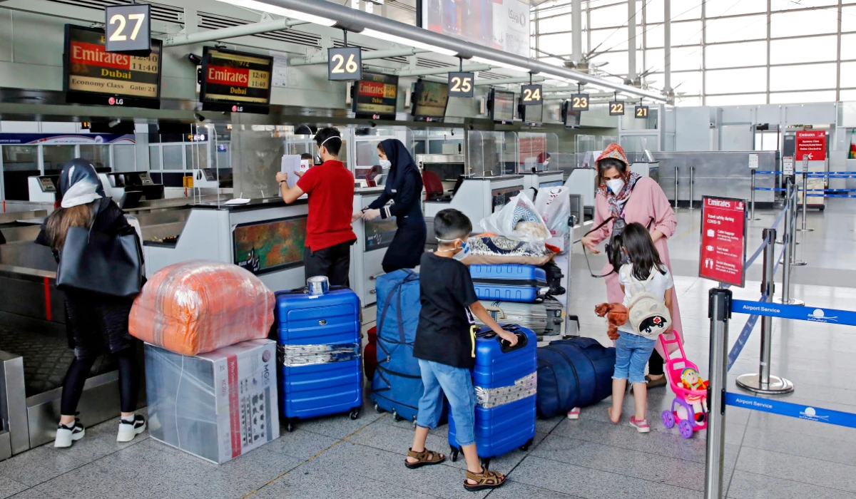 Outbound passengers arrive with their luggage at the Emirates check-in counter at the Iranian capital Tehran's Imam Khomeini International Airport on July 17, 2020. (AFP)