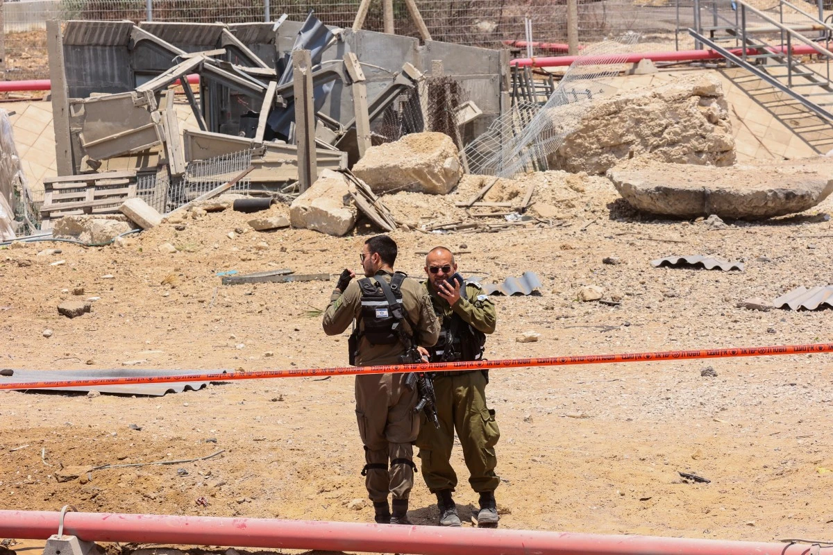 Members of Israeli security forces stand in a cordoned-off area at the impact site of an Iranian rocket near the southern city of Ashdod, June 23, 2025. (AFP)