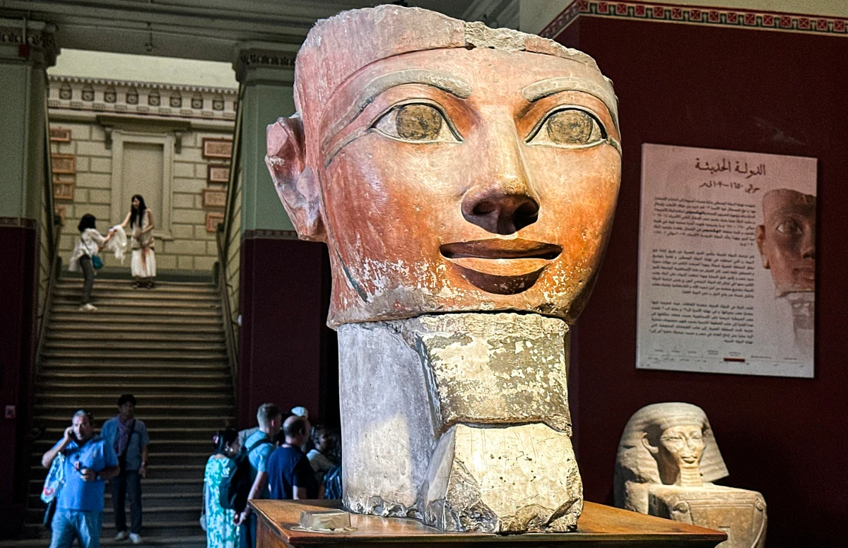 Visitors stand behind the bust of the ancient Egyptian queen Hatshepsut (1479-1458 BC) at the Egyptian Museum in Cairo's central Tahrir Square on June 11, 2025. (AFP)
