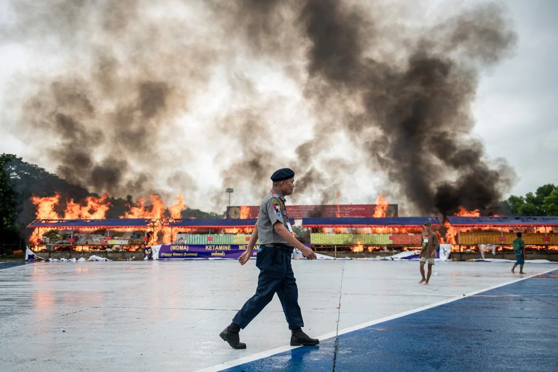 A police officer walks past a burning pile of seized illegal drugs during a destruction ceremony to in Yangon on June 26, 2025. (AFP)