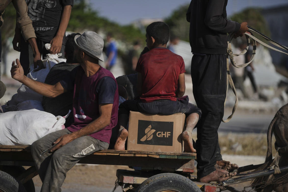 Palestinians carry humanitarian aid packages near the Gaza Humanitarian Foundation distribution center in Khan Younis. (AP)