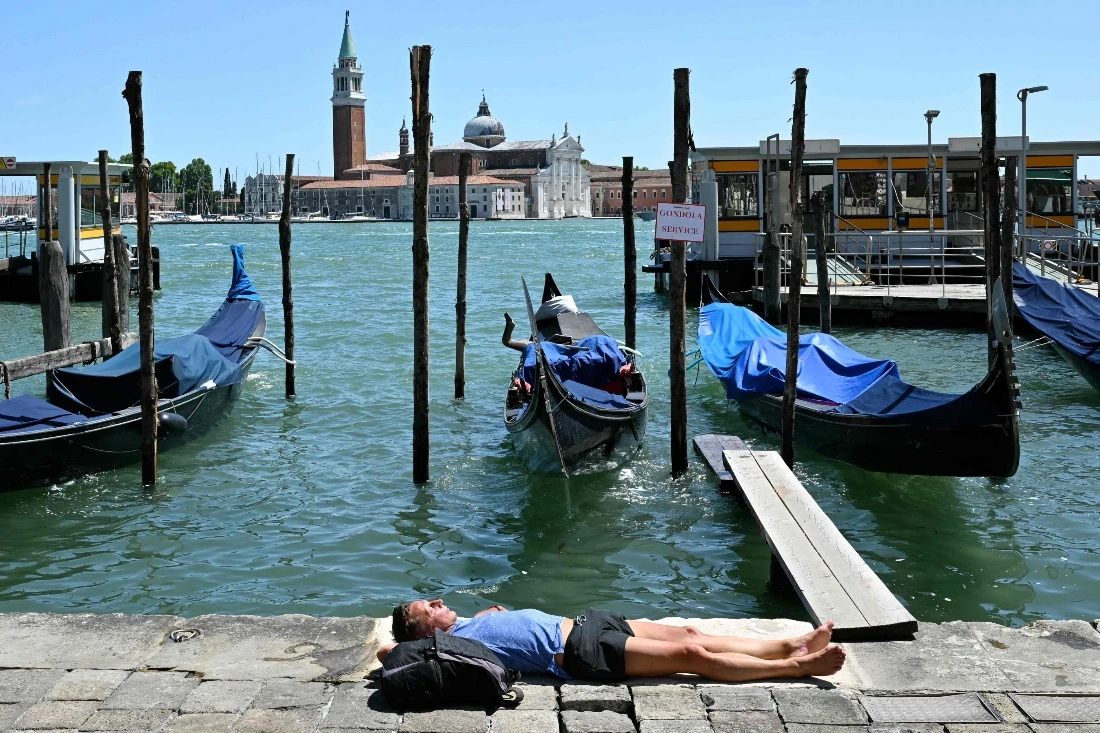 A man rests in front of gondolas on a hot summer day in Venice, Italy. (AFP)
