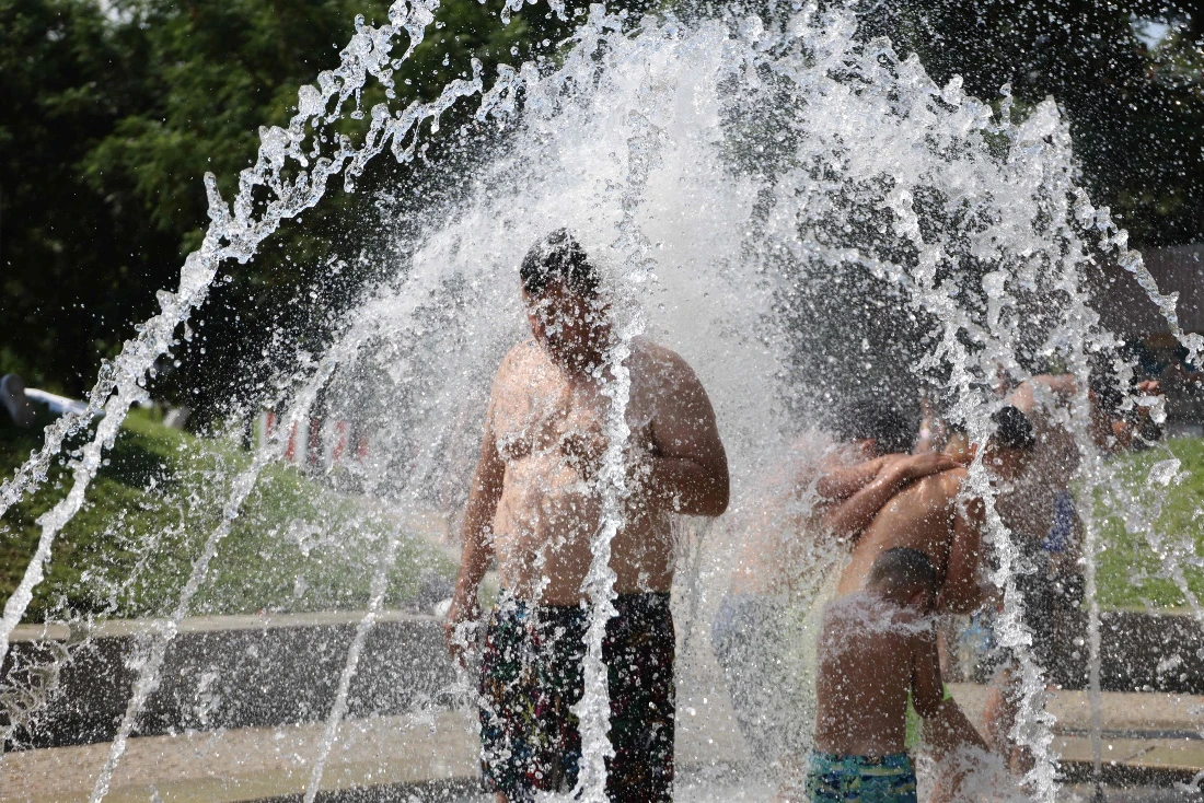 People cool off underneath water fountains in the Madrid Rio recreation area during the first heatwave of the summer in Madrid, Spain. (AFP)