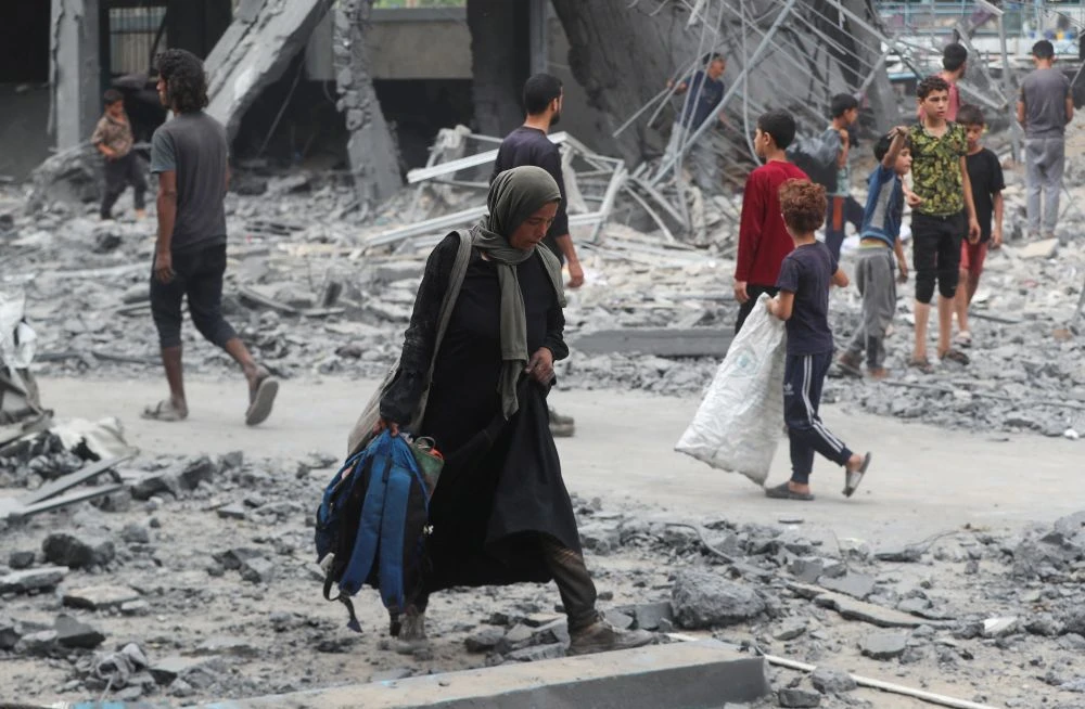 A Palestinian woman walks at the damaged site of an UNRWA school sheltering displaced people that was hit in an Israeli air strike on Sunday, in Gaza City, June 30, 2025. (Reuters)