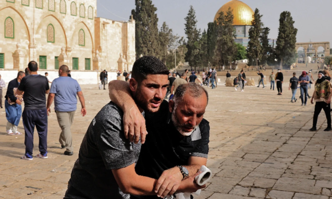 A Palestinianman helps a wounded fellow protester amid clashes with Israeli security forces at Jerusalem's Al-Aqsa mosque. (AFP)