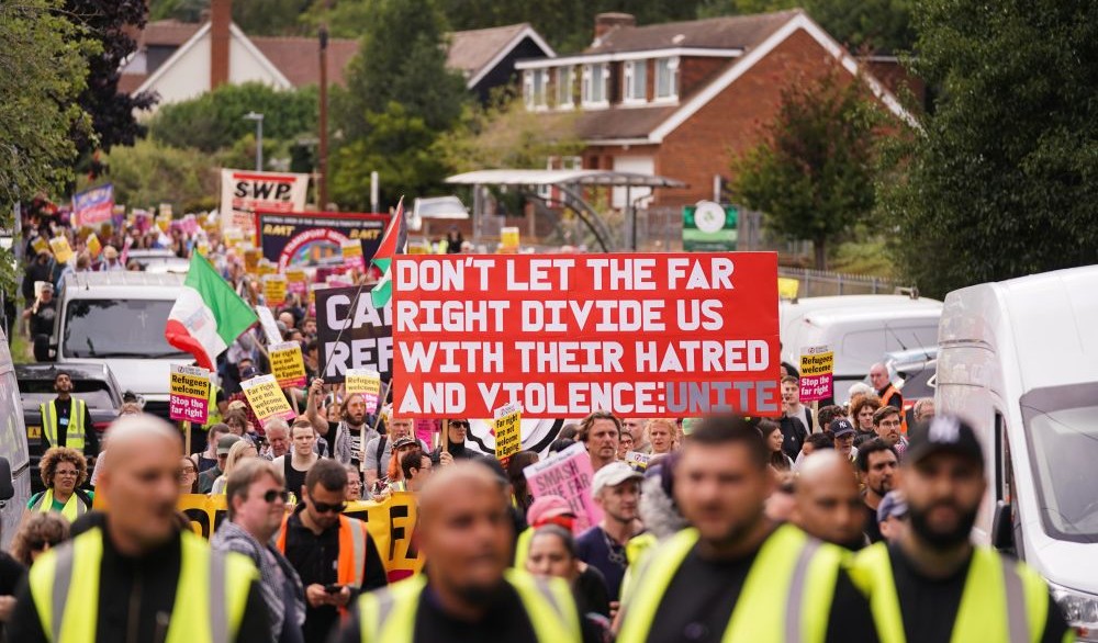 Demonstrators hold placards and banners as they leave a protest outside the Bell Hotel, Epping, July 27, 2025. (AP Photo)
