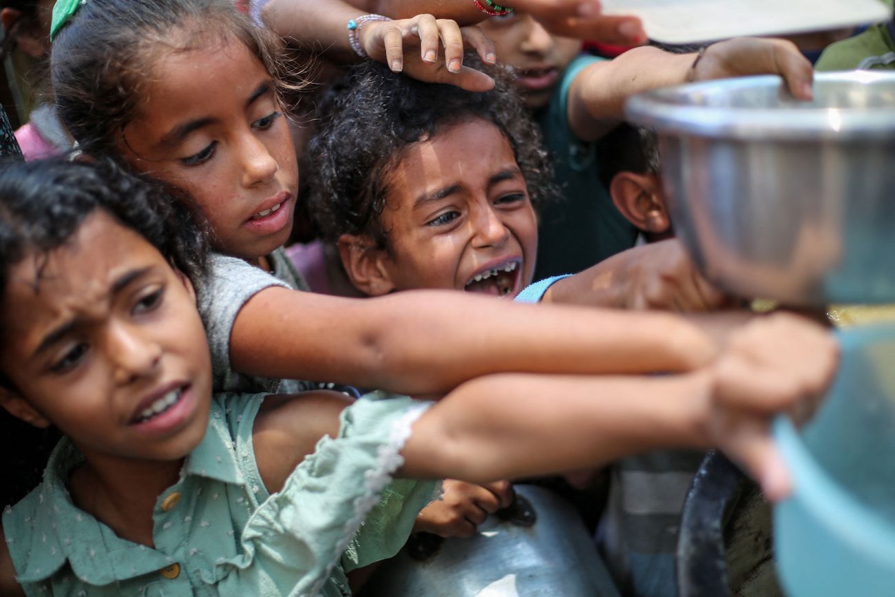 Palestinian children line up to receive a hot meal at a food distribution point in Nuseirat on June 30, 2025. (AFP)