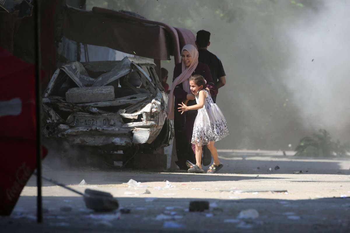 A Palestinian mother and her daughter rush for cover during an Israeli strike in the Al-Bureij camp in the central Gaza Strip on July 4, 2025. (AFP)