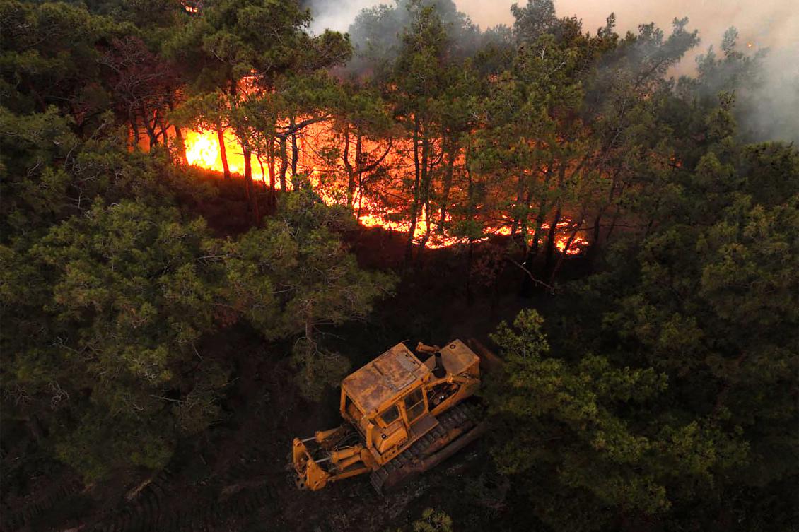 This handout picture released by the Syrian Arab News Agency’s (SANA) telegram page shows a bulldozer attemping to contain a wildfire sweeping through Qatal Maaf in the Latakia province in Syria’s Mediterranean West on July 4, 2025. (AFP)