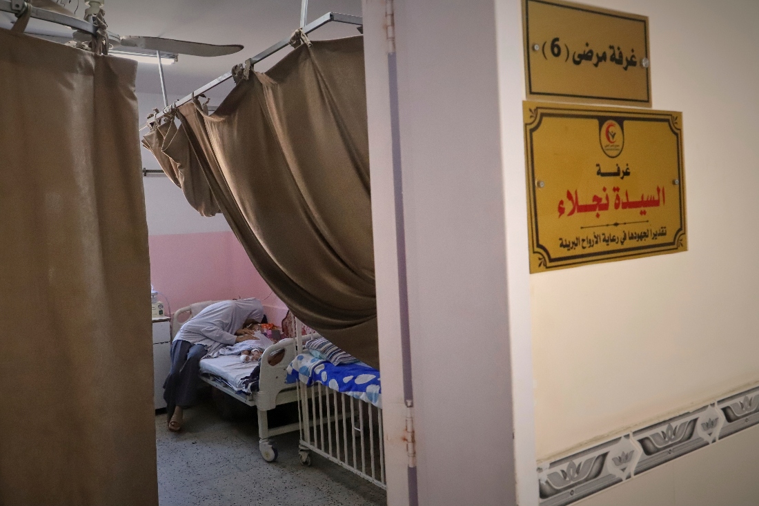 Amr Al Hams's aunt comforts him as he lies in a hospital bed with brain damage caused by an Israeli strike on his family's tent in April, at Nasser Hospital in Khan Younis, Gaza Strip. (AP)