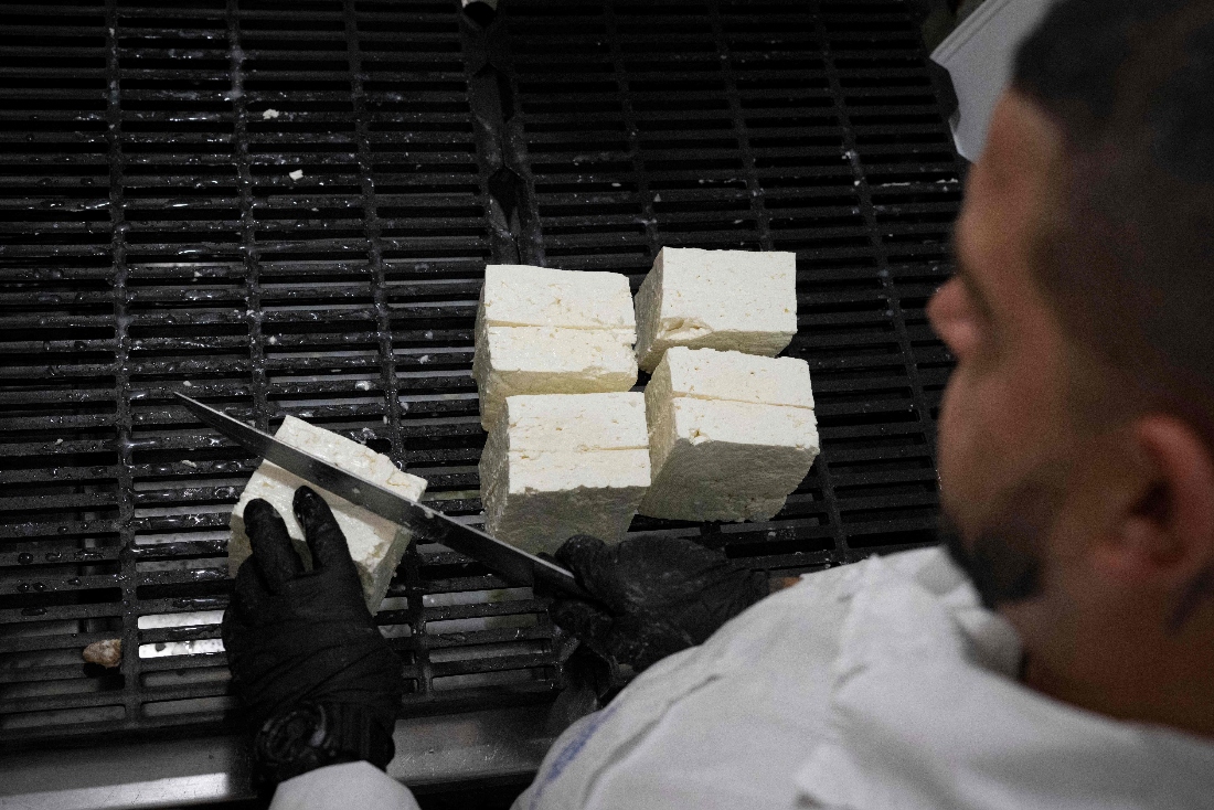 An inmate cuts on pieces white cheese at the "Gerzovitsa" dairy in the Smolyan prison in Bulgaria. (AFP)