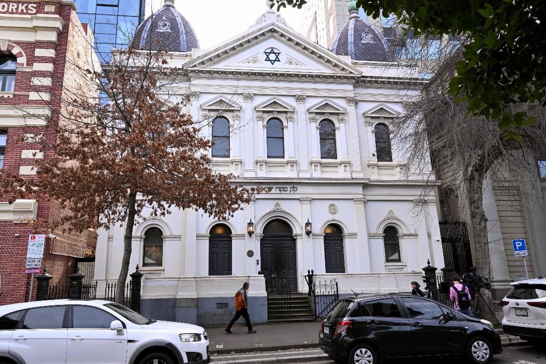 People pass the burnt front entrance of the East Melbourne Synagogue in Melbourne, Australia. (AFP)