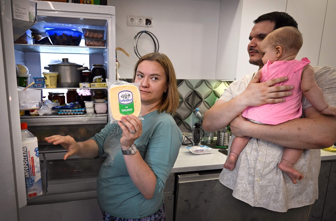 Maria Tyabut shows off the food stored in her new Chinese made refrigerator while her husband Sergei Duzhikov holds their daughter Yekaterina at their apartment in the Moscow suburb of Mytishchi, Russia. (AFP)