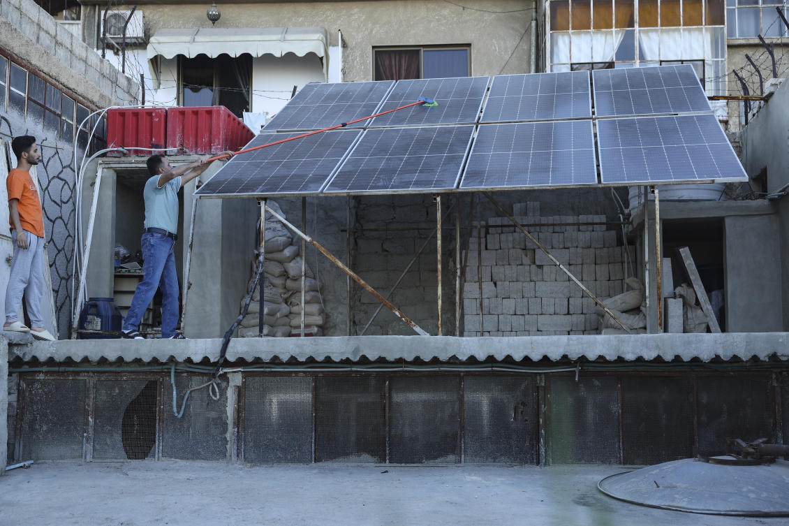A Syrian man Abdul Razzaq Al-Jenan, cleans solar panels that set on his house roof, in Damascus, Syria, Sunday, June 29, 2025. (AP)