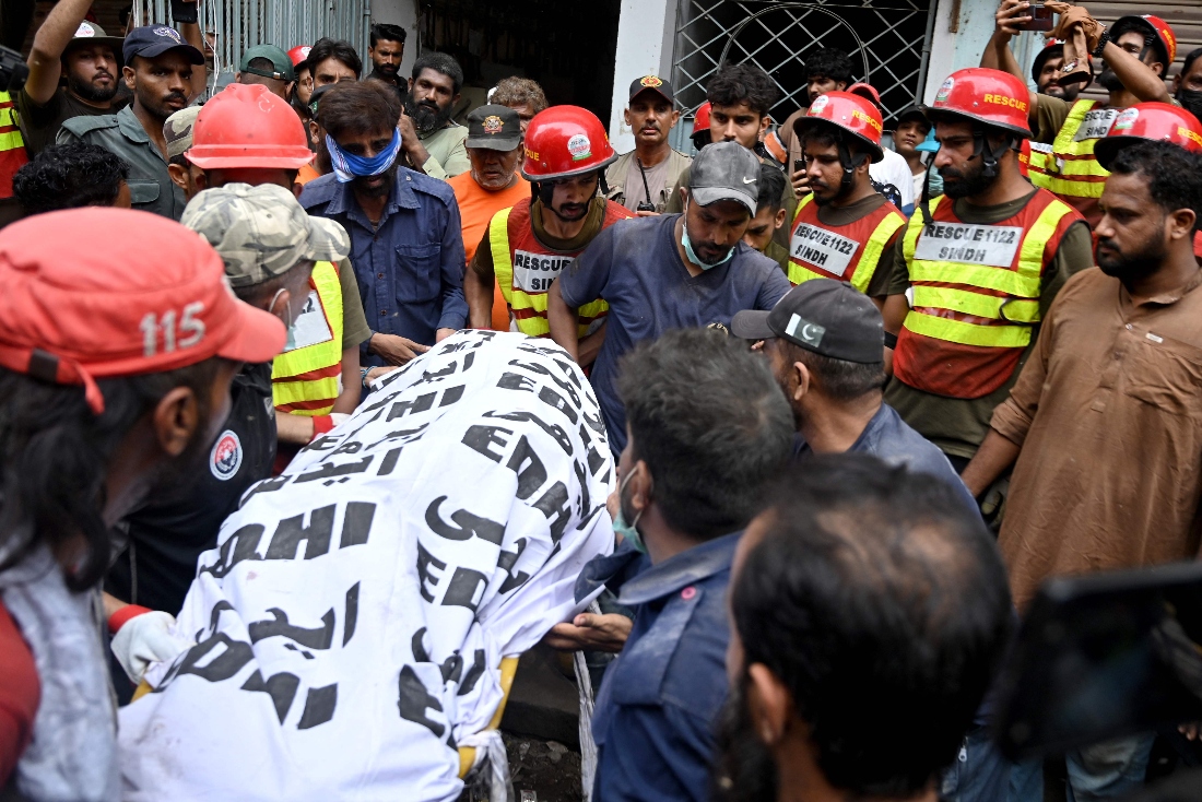 Rescue workers recover a victim's body during a search operation amid the debris of a collapsed residential building in Karachi, Pakistan. (AFP)