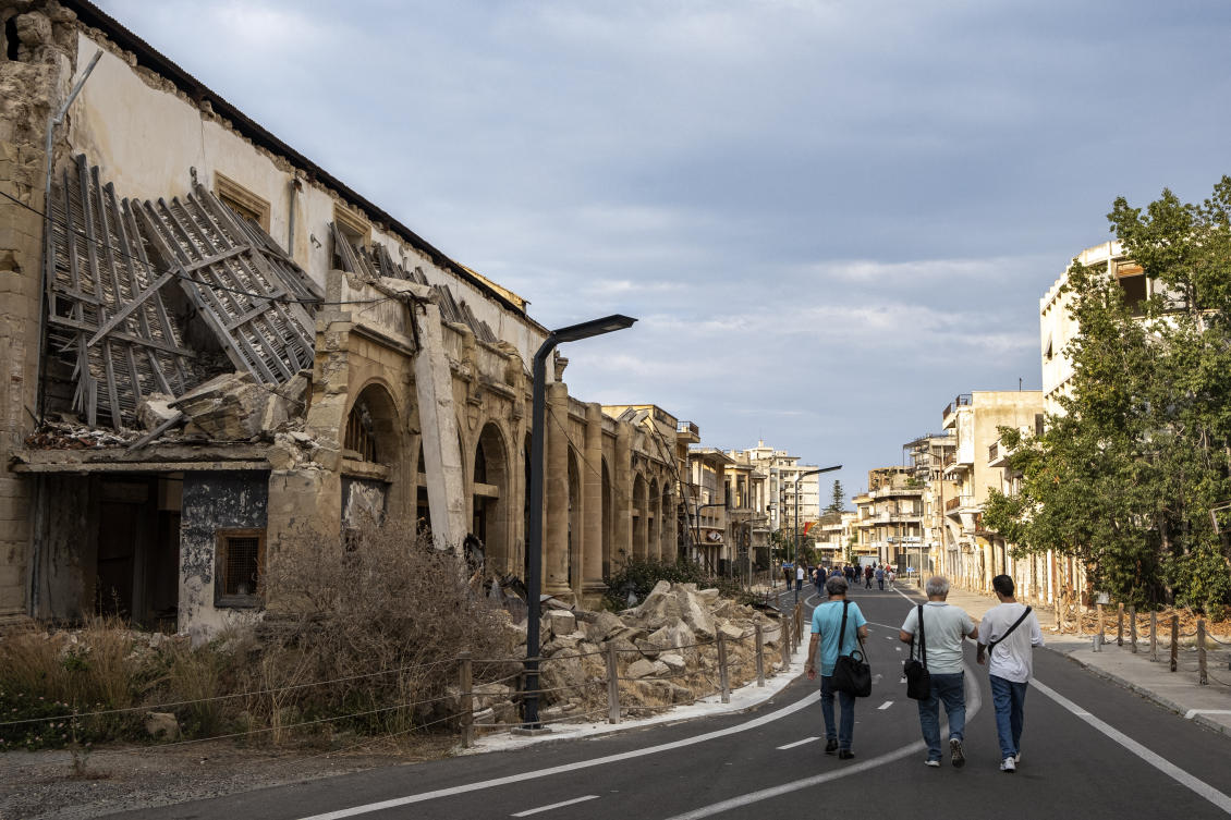 Journalists walk during an organized tour past partially collapsed abandoned buildings in Varosha, in the fenced off area of Famagusta, in the Turkish-controlled north of the divided eastern Mediterranean island of Cyprus. (FILE/AFP)