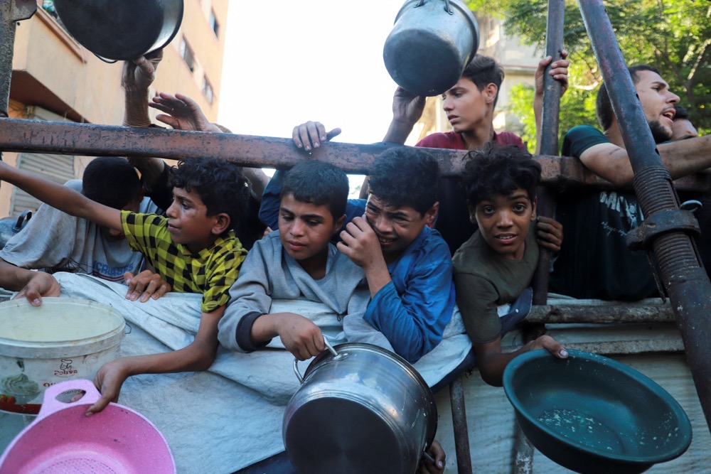 Palestinians react as they ask for food from a charity kitchen, amid a hunger crisis, in Gaza City. (Reuters)