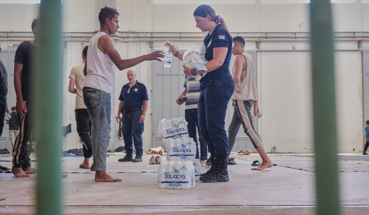 A Greek coast guard gives water to migrants from Africa as they take a shelter in Agia port, Chania, Crete island, Greece, Monday, July 7, 2025. (AP)