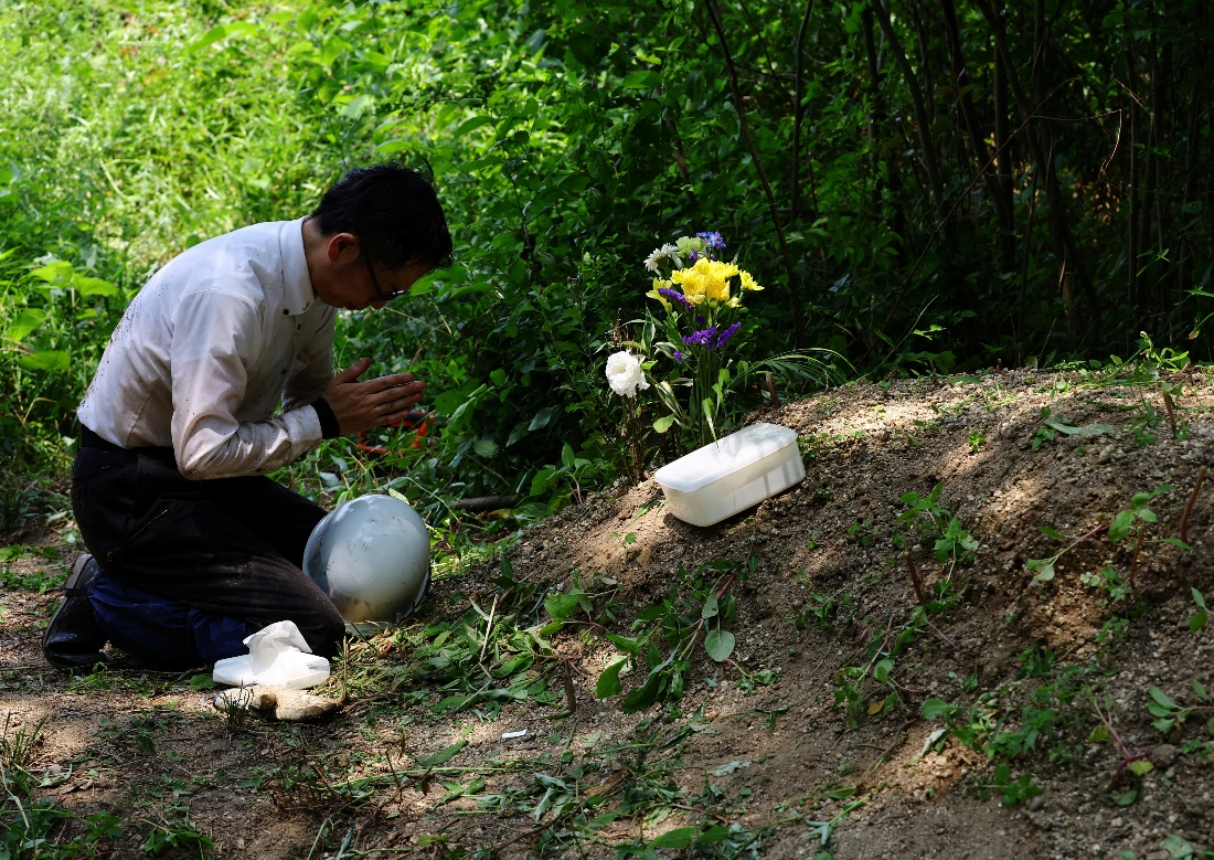 Rebun Kayo offers a prayer to the bone fragments he has found and placed in a plastic box at a site on Ninoshima Island, Japan. (Reuters)
