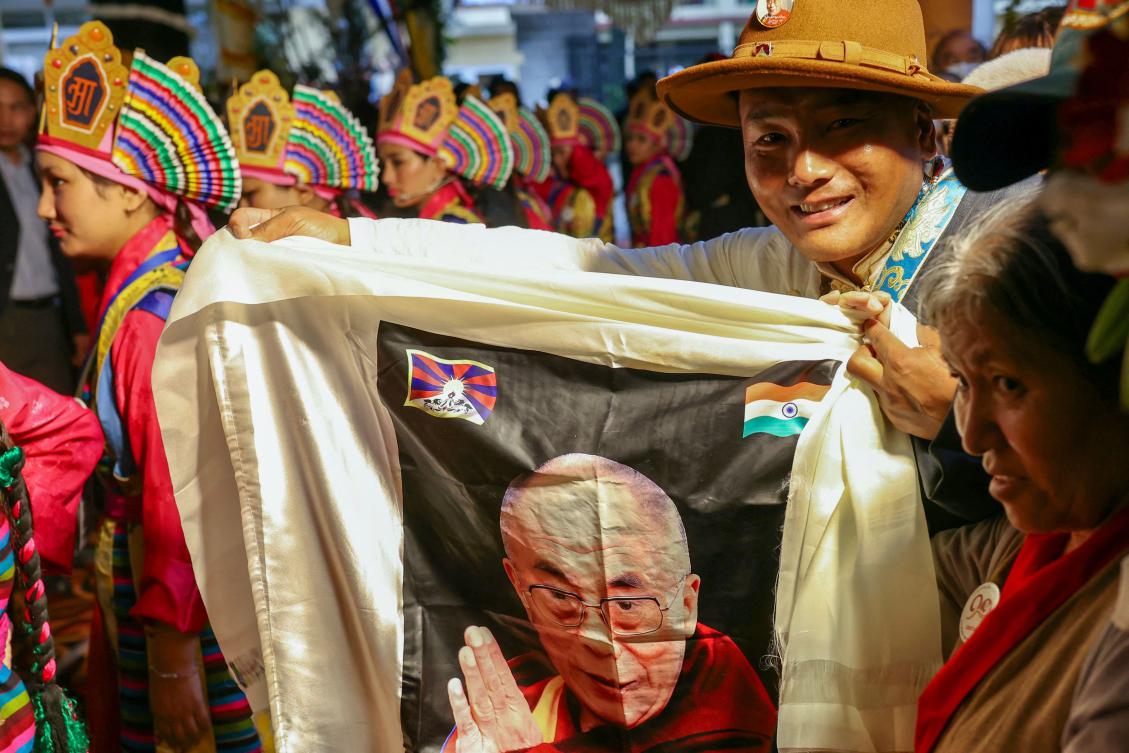 A devotee carries a cloth with a print with birthday wishes for Tibetan spiritual leader the Dalai Lama during a prayer ceremony celebrating his 90th birthday at the Main Tibetan Temple in McLeod Ganj, near Dharamsala, on July 6, 2025. (AFP)