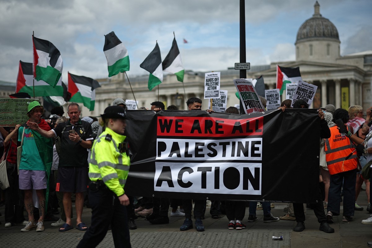 Police officers monitor protesters holding a banner during a protest in support of pro-Palestinian group Palestine Action, in Trafalgar Square. (File/AFP)