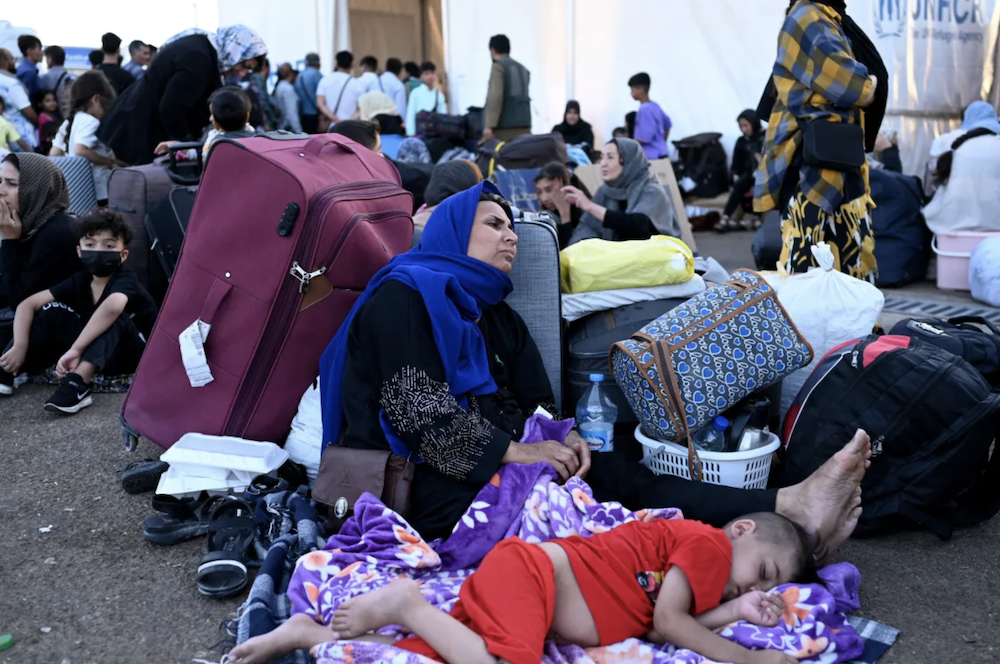 Afghan refugees rest with their belongings after arriving at the zero point of the Islam Qala border crossing between Afghanistan and Iran, following their deportation from Iran. (AFP)