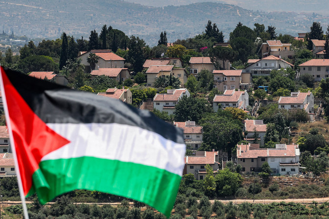 A Palestinian flag flies opposite Israeli settlements in the occupied West Bank. A postponed Saudi-Franco conference to discuss Palestinian statehood has been rescheduled for July 28 to 29. (AFP/File Photo)