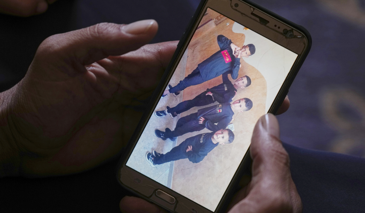 Hatem Al-Nouri shows a photo of his children Amir, 4, right, and Omar, 8, second from right, accompanied by their brothers, as he talks about when the two were killed in an Israeli strike while waiting to receive nutritional supplements at a medical clinic, during an interview at his home in Deir al-Balah, Gaza Strip, Friday, July 11, 2025. (AP)