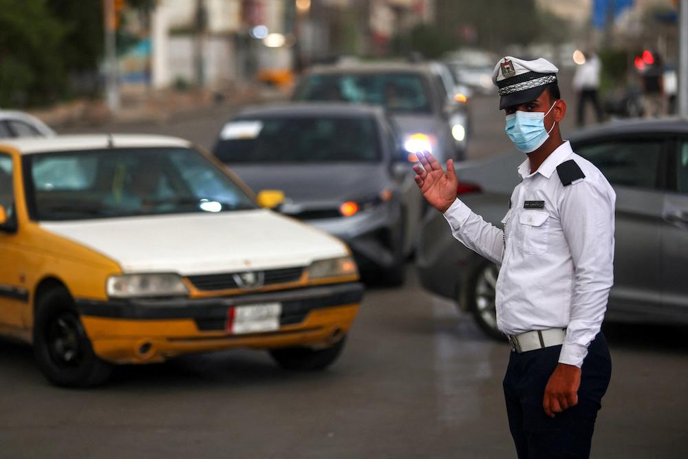 Above, a police officer directs traffic during a sand storm in the Iraqi capital Baghdad on May 1, 2025. Severe storms in Iraq have overwhelmed hospitals with respiratory cases. (AFP)