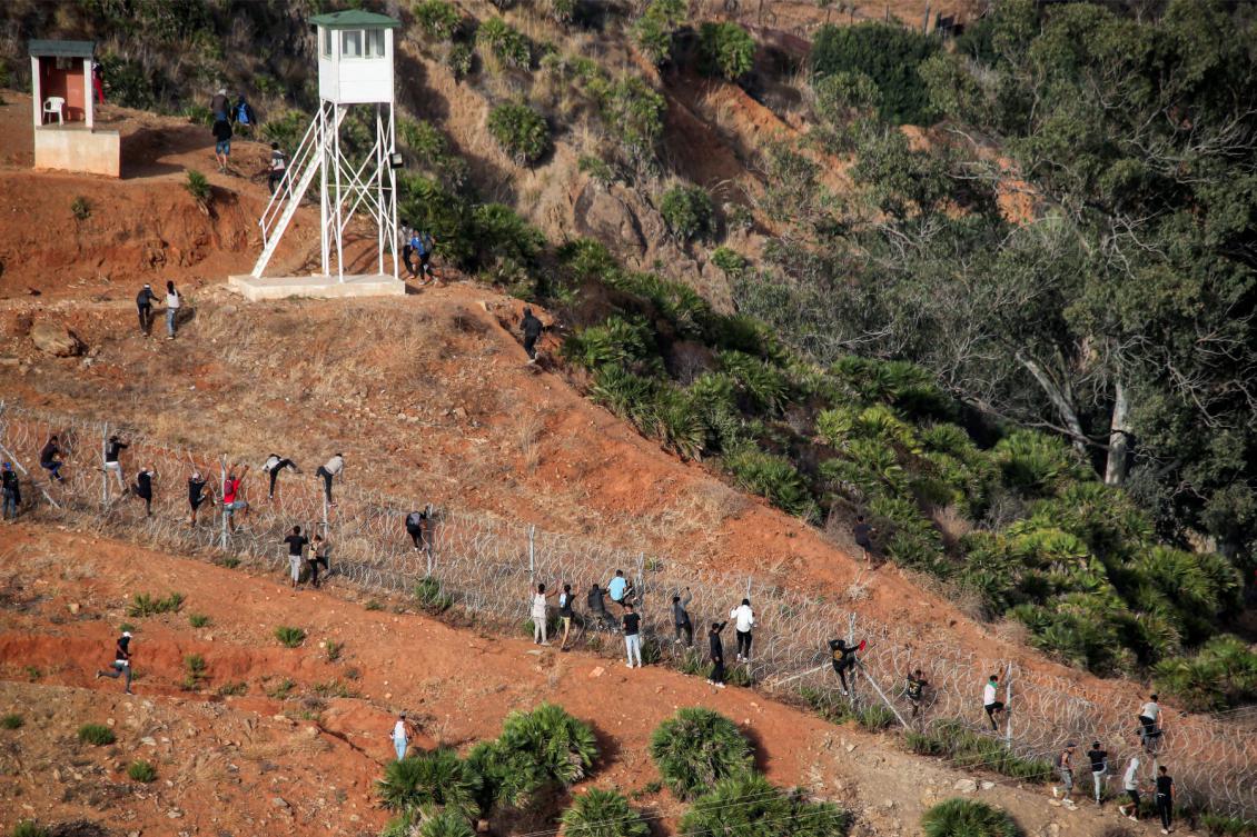 Migrants storm a barbed-wire fence as they attempt to cross the land border with Spain's African enclave of Ceuta near Fnideq in northern Morocco on September 15, 2024. (AFP)