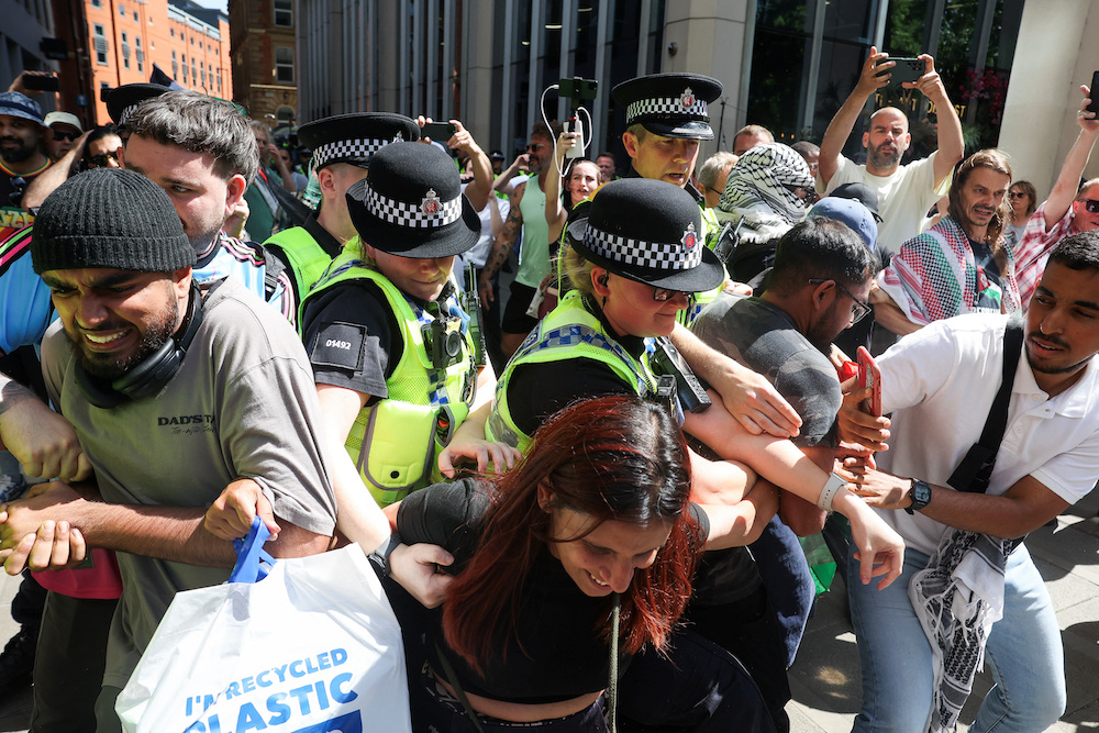 Police officers try to stop demonstrators from linking arms, during a protest calling for the de-proscription of the Palestine Action group, at St. Peter’s Square in Manchester, Britain, July 12, 2025. (Reuters)