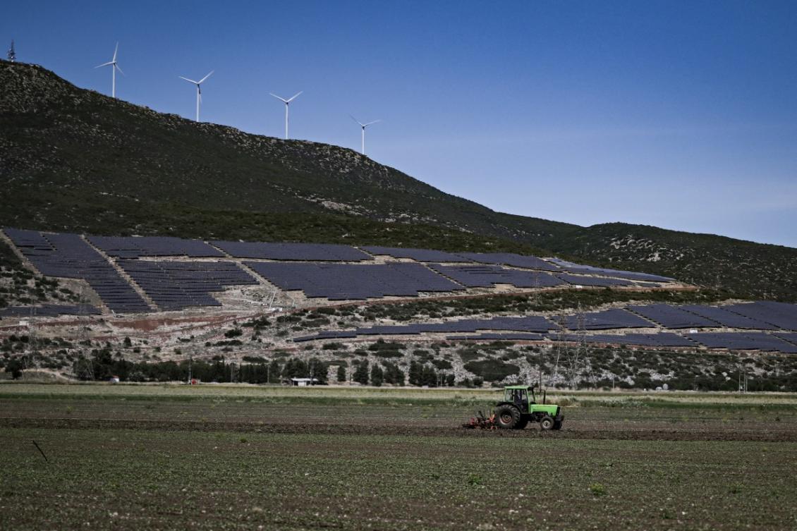 This picture taken on May 20, 2025, shows a farmer on his tractor plowing a field in front of a solar energy farm near Kastro Viotias. . (File/AFP)