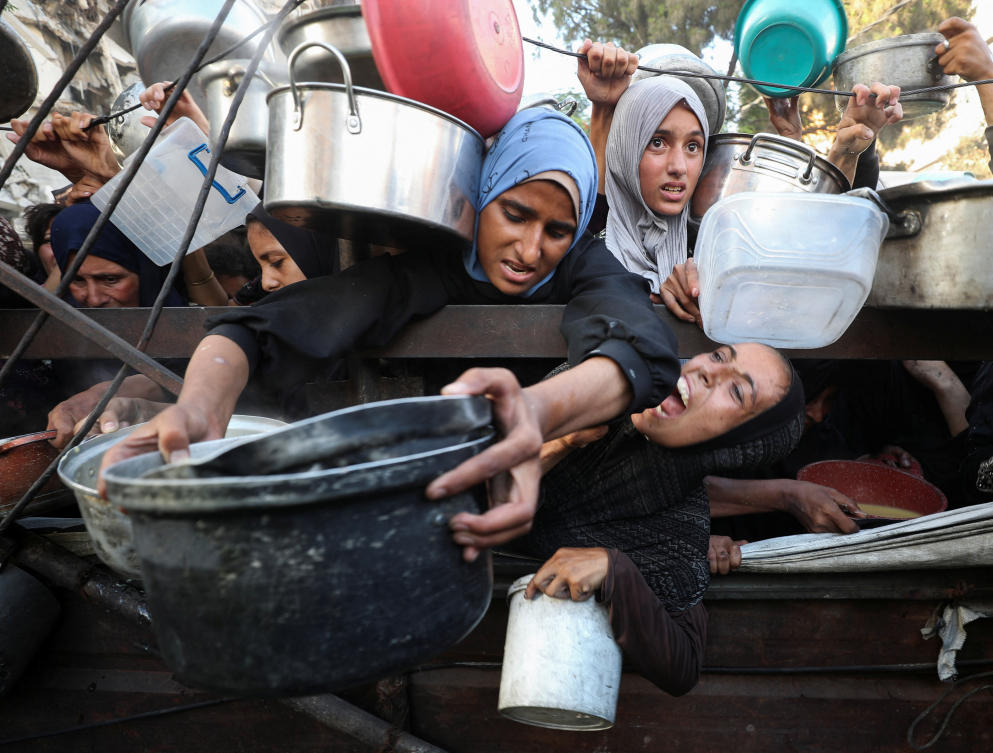 Palestinians react as they ask for food from a charity kitchen, amid a hunger crisis, in Gaza City, July 14, 2025. (Reuters)