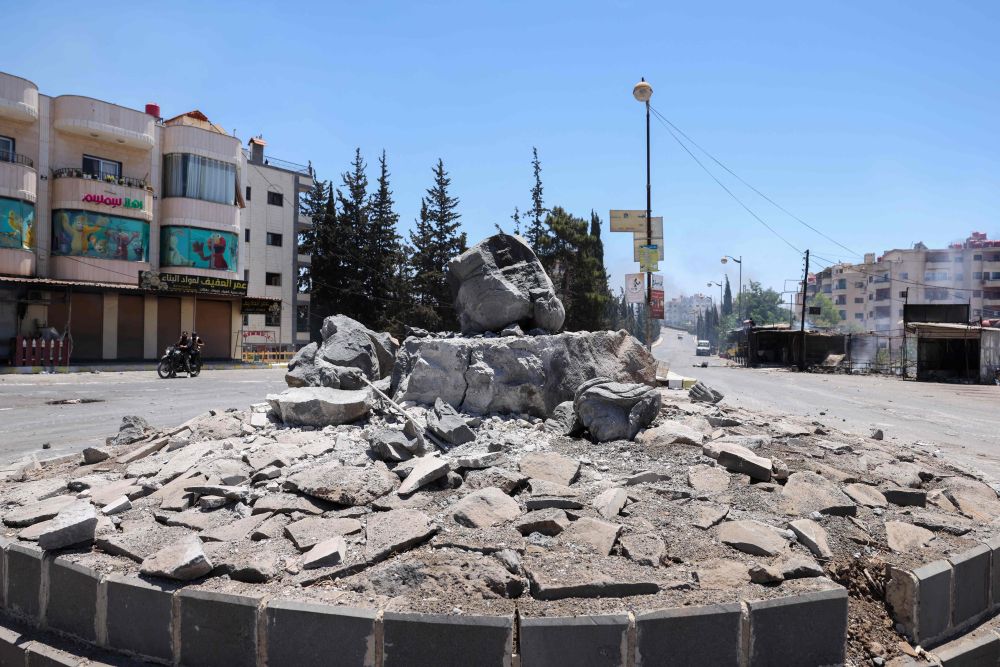 Members of Syria’s security forces ride their motorcycle past a destroyed monument in the predominantly Druze city of Suwayda, July 15, 2025. (AFP)