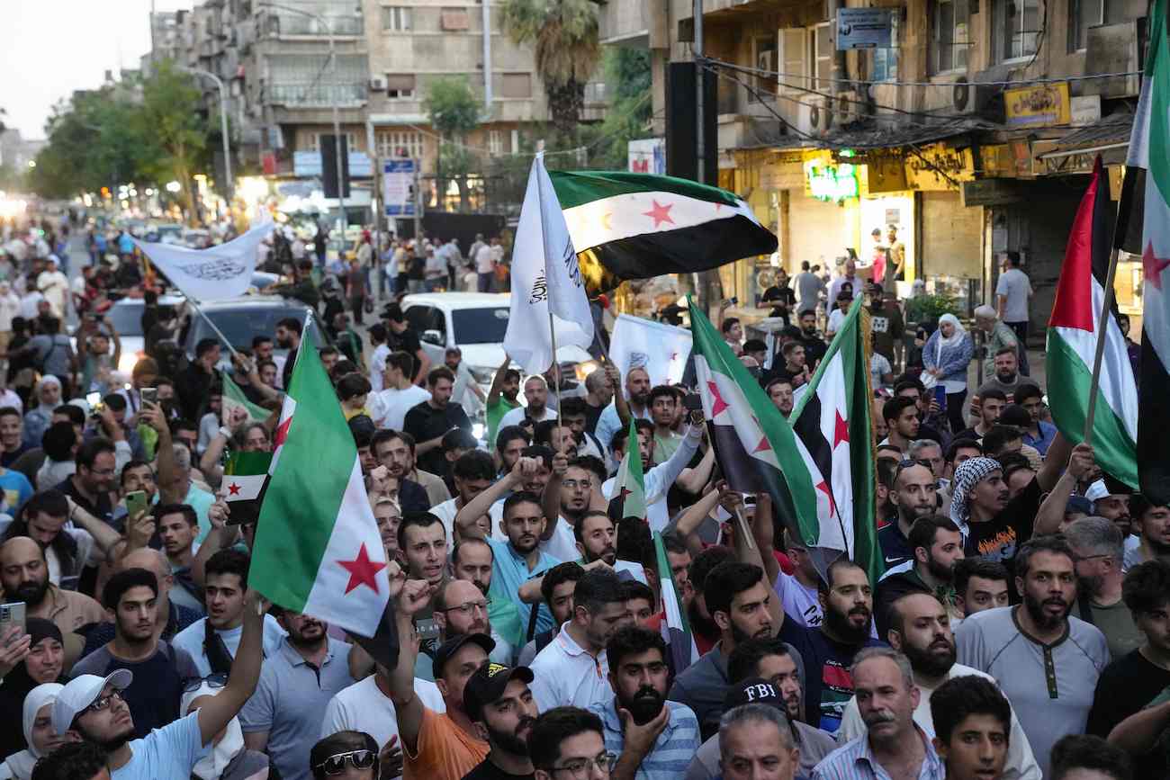 Syrians wave flags during a demonstration against Israeli intervention in Syria, in Damascus on July 16, 2025. (AFP)