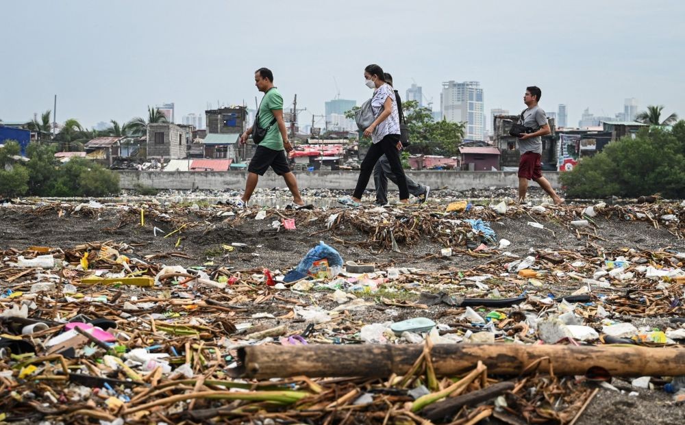 Residents walk past trash including plastic waste strewn along Baseco Beach in Manila on September 21, 2024. (AFP)