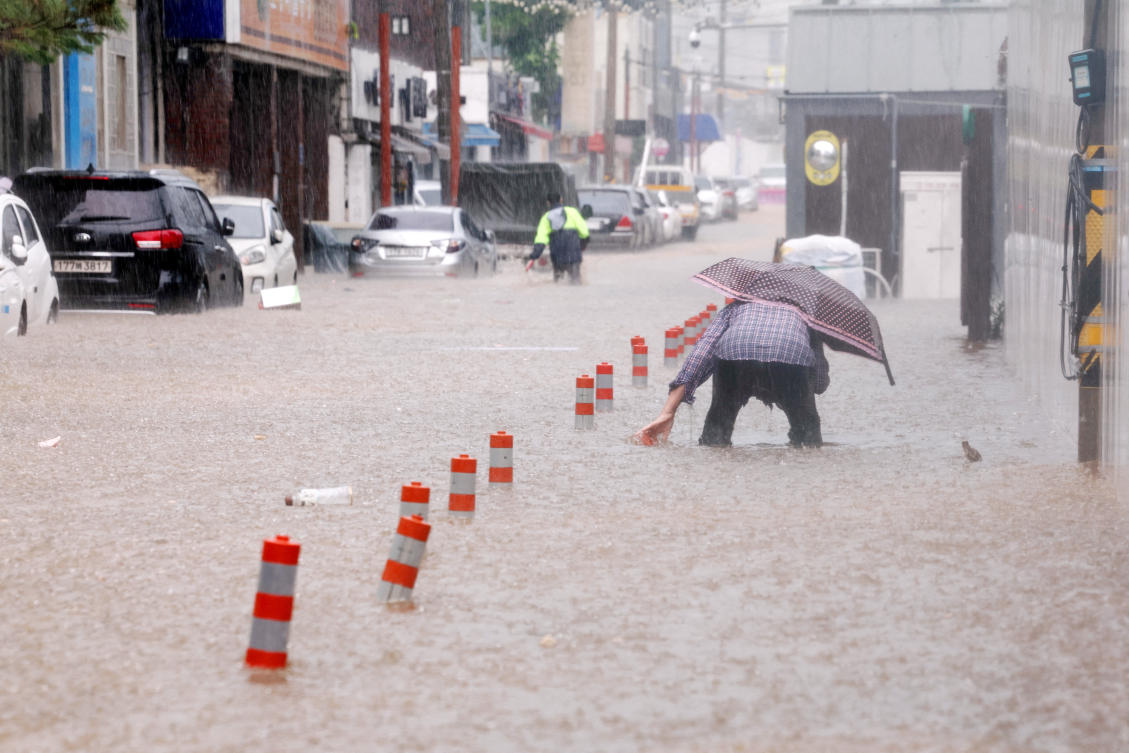 A man makes his way through a flooded street, caused by torrential rain, in Gwangju, South Korea. (REUTERS)
