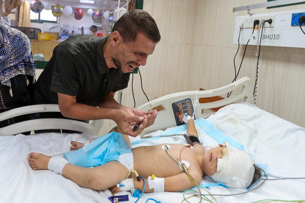 Palestinian father Hatem Al-Nouri, who lost two of his children, Omar and Amir, in the July 10 Israeli strike while they were queuing for supplements near a medical center, reacts as he accompanies his son Siraj, who was wounded in the same strike, at Al-Aqsa Martyrs Hospital in Deir al-Balah, in the central Gaza Strip, July 14, 2025. (Reuters)
