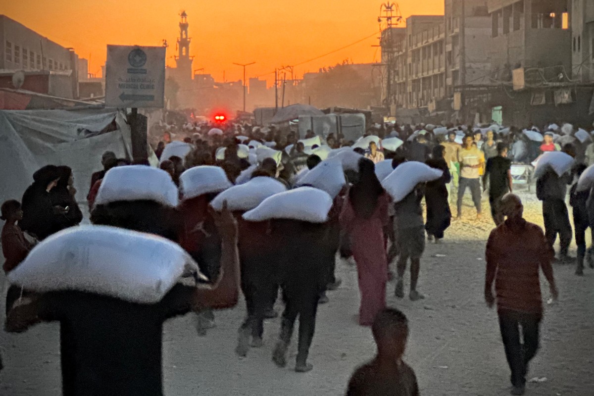 Men walk carrying sacks of flour in Khan Yunis, southern Gaza Strip, July 22, 2025. (Agence France-Presse)