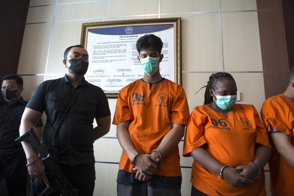 An Indonesian Narcotics Agency officer escorts a Brazilian national identified as YB, center, and South African national identified as LN, right, who were arrested on accusation of smuggling cocaine into the resort island of Bali, during a press conference in Denpasar, Indonesia, Thursday, July 24, 2025. (AP)