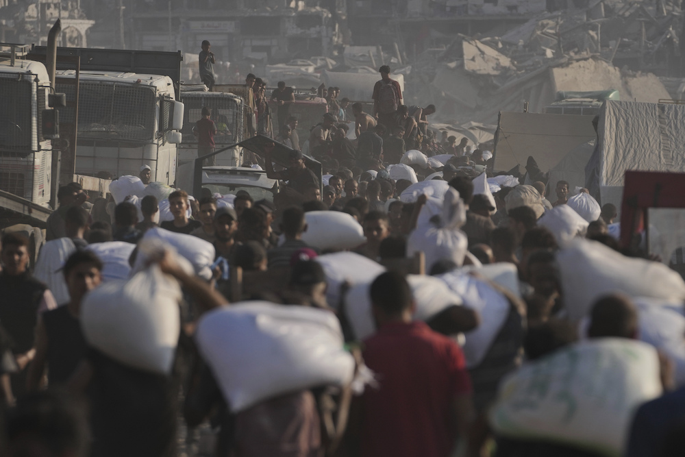 Palestinians carry sacks of flour unloaded from a humanitarian aid convoy that reached Gaza City from the northern Gaza Strip, Saturday, July 26, 2025. (AP)