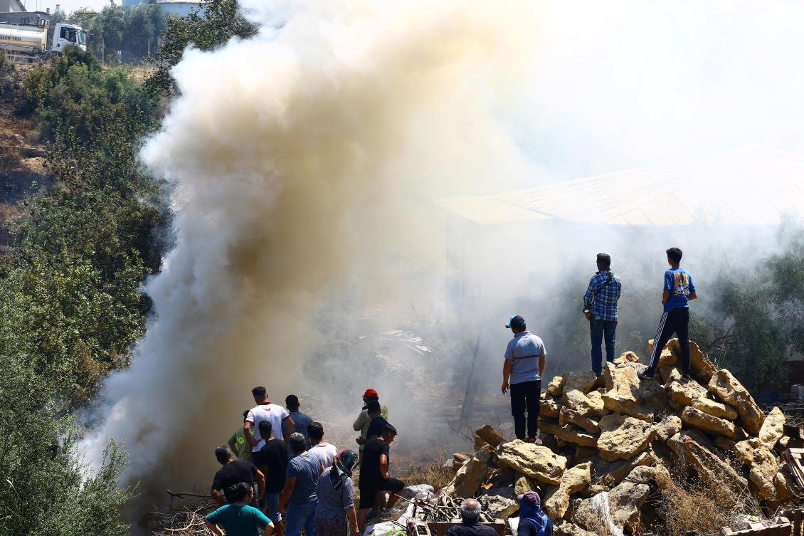 Turkiye has been hit by dozens of wildfires daily since late June. Above, people stand next to smoke rising from the wildfire in the Aksu district of Antalya in southern Turkiye on July 25, 2025. (Reuters)